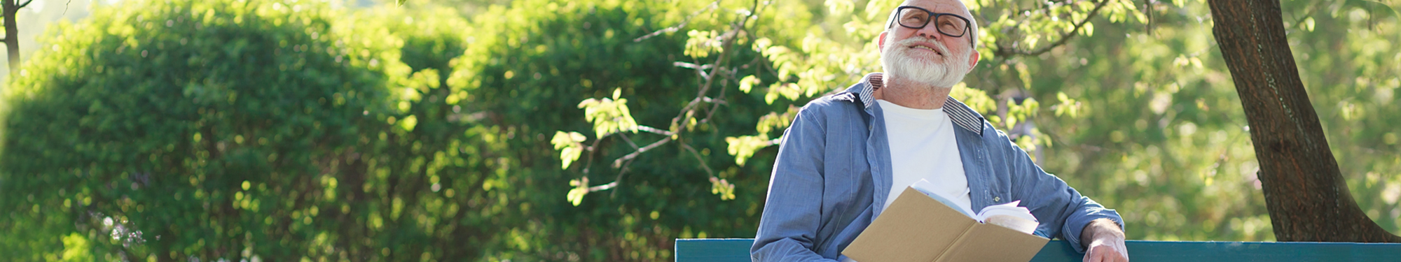 older man sitting on a bench, reading an book